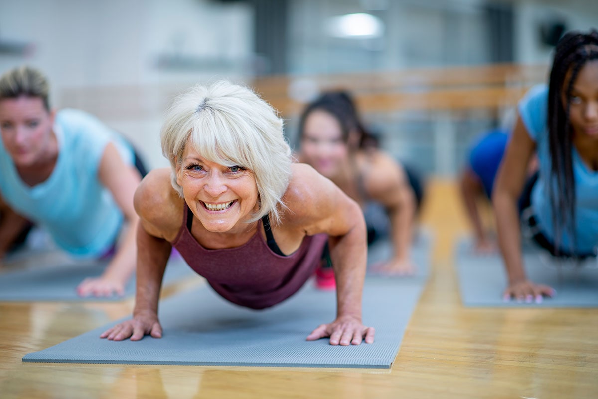 Smiling Senior Woman in Fitness Class in a Plank Pose